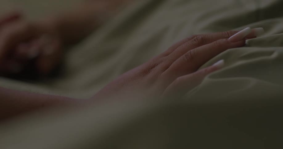 A woman is holding a male patients hand while on the hospital bed