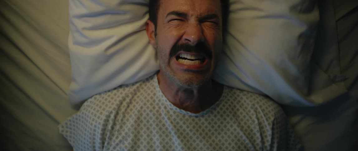 The patient screams in pain while laying in the hospital bed