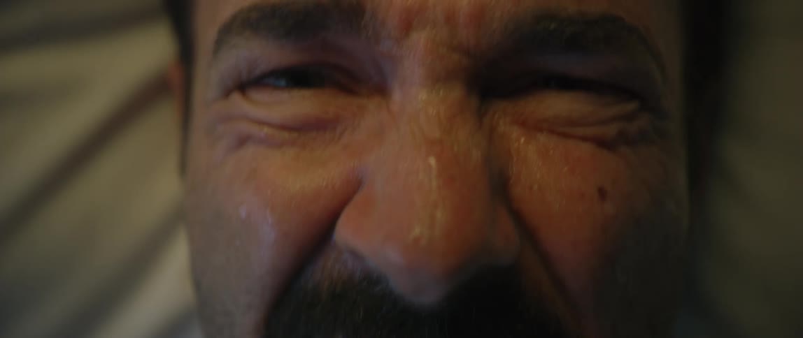 Man winces and closes his eyes