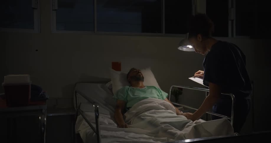 A concerned nurse gently checks on a patient lying in a hospital bed offering care and attention