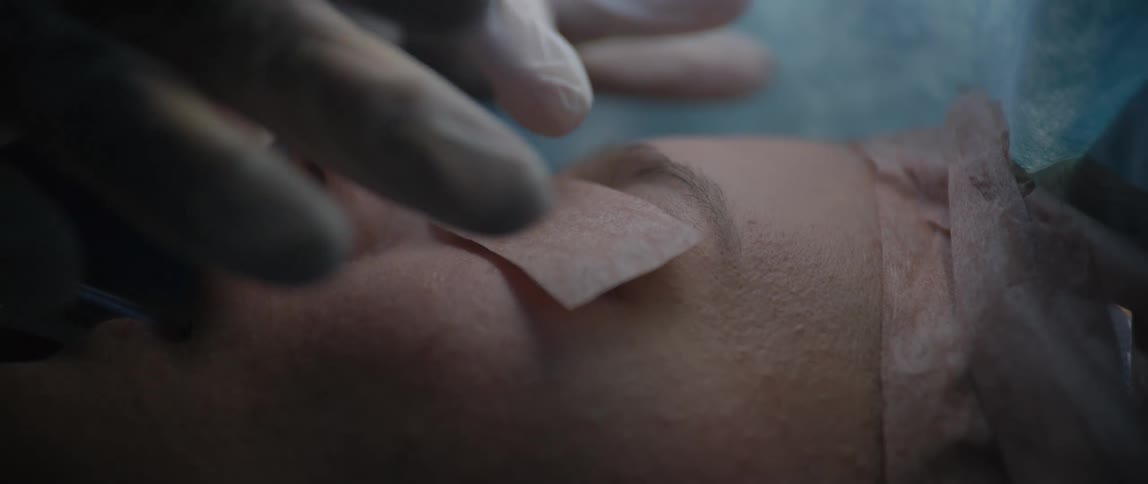 Medical professional placing medical tape on patients eyelids before surgery