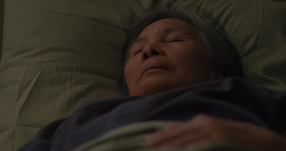 The elderly woman is sleeping in the bed