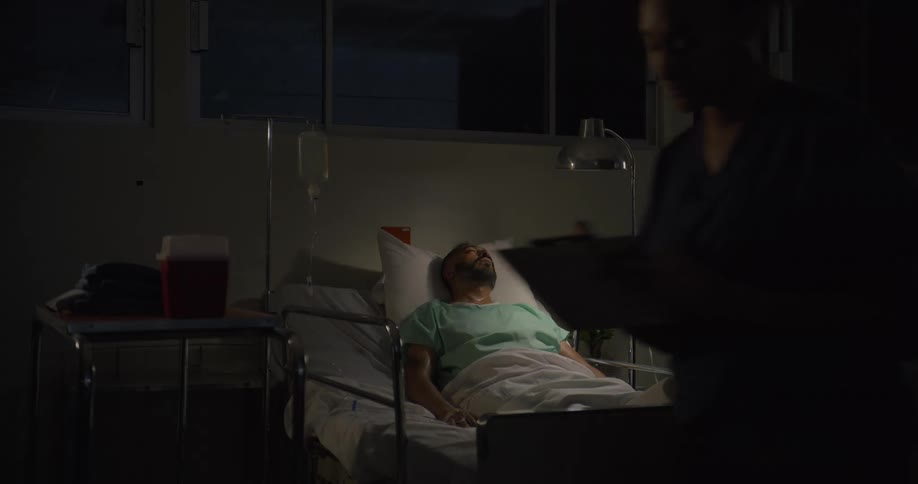 The nurse checks on a patient in the hospital bed