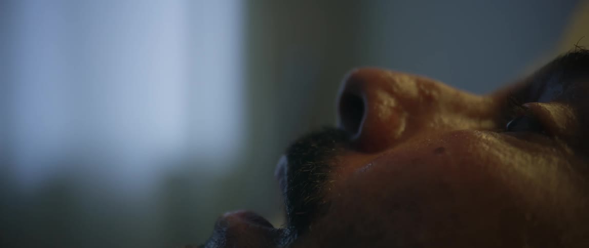 A man winces in pain while laying in a bed