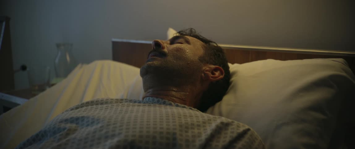 A man lies in a hospital bed sweating and unwell conveying a tense and potentially lifethreatening medical situation