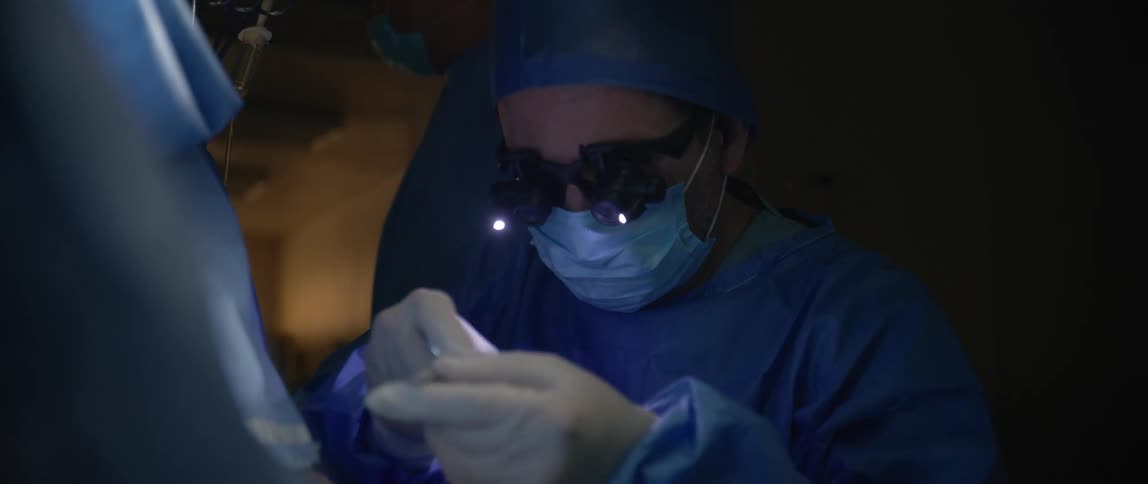 Medical professional wears surgical loupes while using scissors during a medical procedure