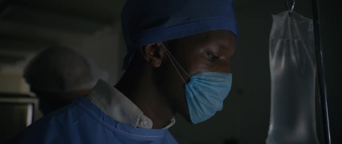 A doctor in a hospital observes and nods yes behind him another doctor is moving