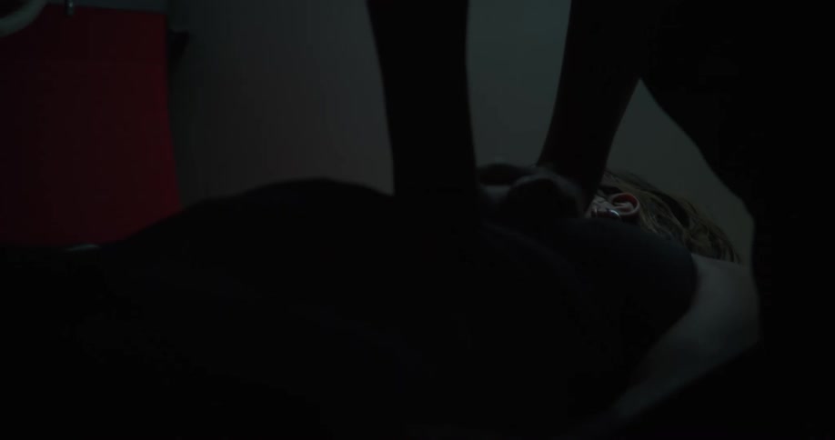A woman laying on a table receives heart compressions and shocks from 2 other people