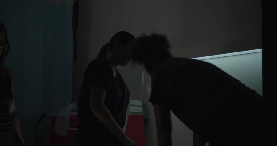 A doctor is giving chest compressions in the hospital while a visitor watches