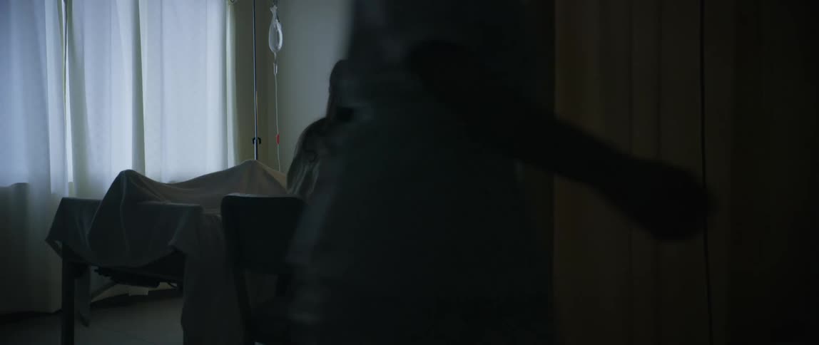 A man screams in pain in the hospital bed as a visitor cries