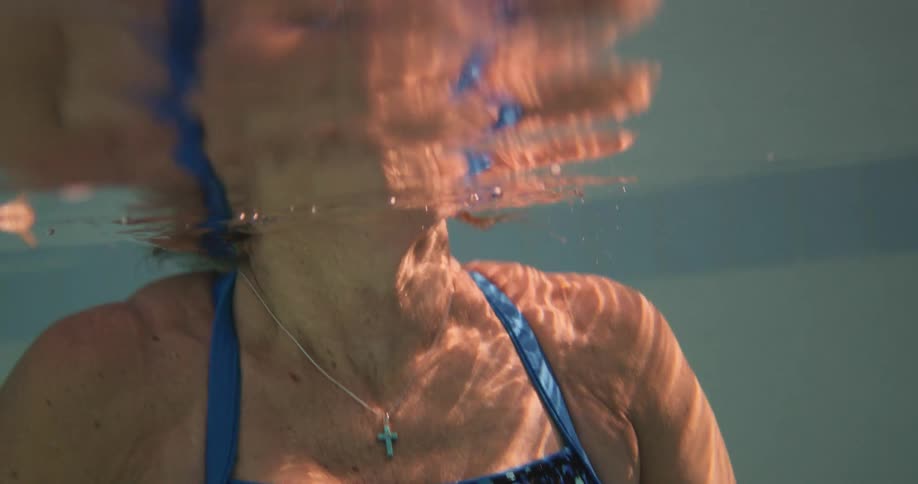 A woman comes up from underwater in her pool