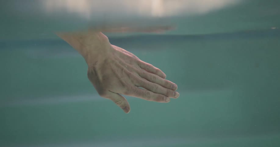A person puts their hand into the water and then drags it out