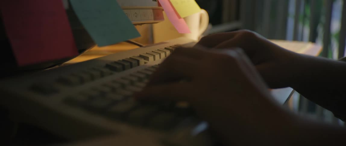 A person sits at their desk and types on the keyboard