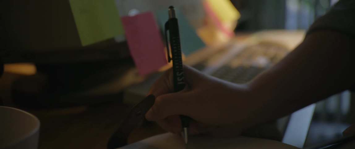 A person writes with a pen in a notebook