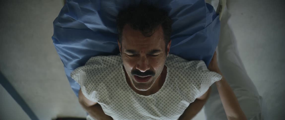 Male patient winces and frowns as he lays on a stretcher
