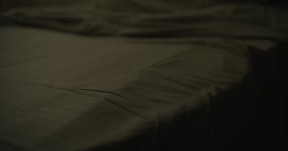 A sheet is on the bed in a dark room