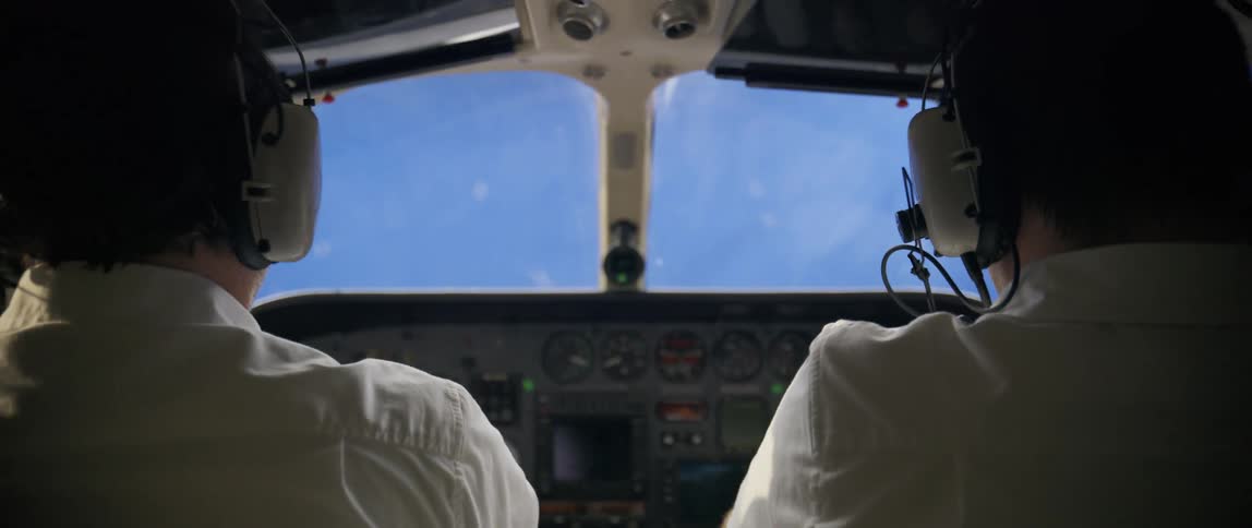 Three pilots intently focus within a simulated flight environment as they navigate a training exercise in the cockpit