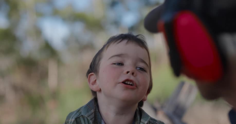 A father listens to headphones as his son laughs at him