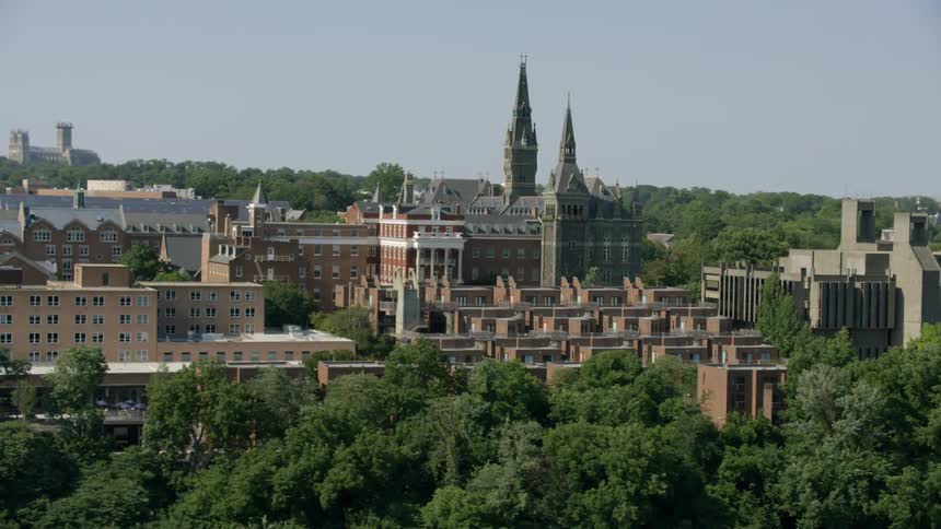Old buildings rise above trees on a hill on a clear day
