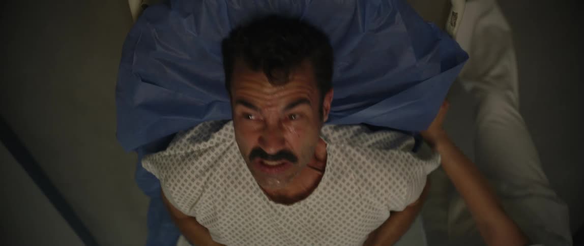 Patient in pain lying on a stretcher being carried down a hospital corridor