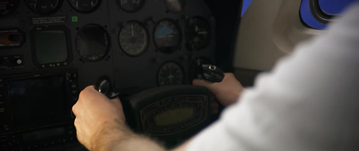 A man piloting an airplane holding the yoke while the plane shakes