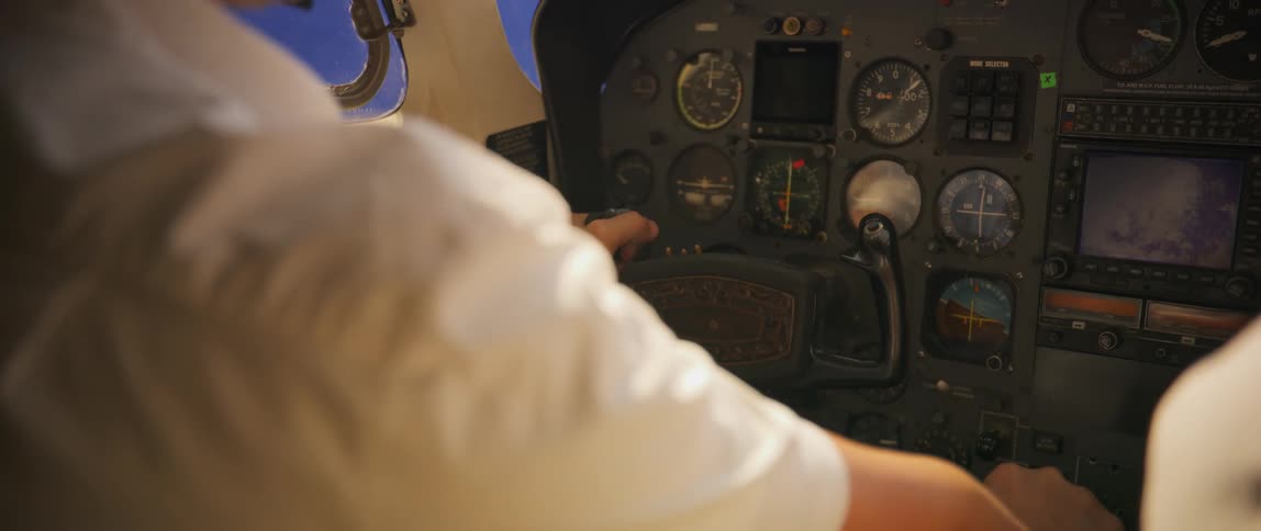 A pilot holds the yoke at the cockpit as he steers an aircraft in the air