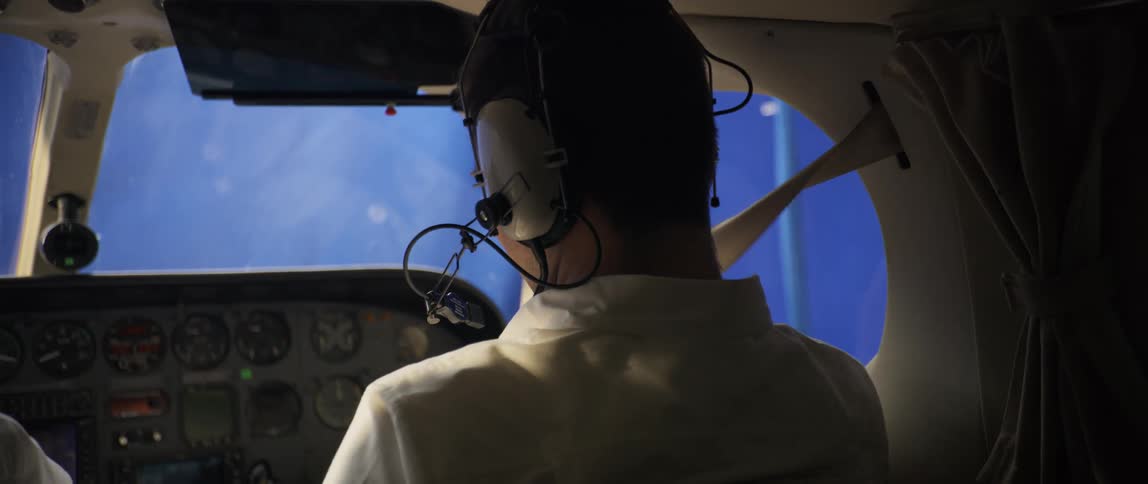 The pilot puts on his seat belt in the cockpit