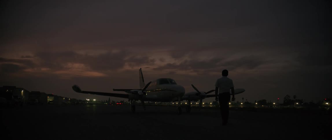 A man walks up to a plane that is parked on the tarmac