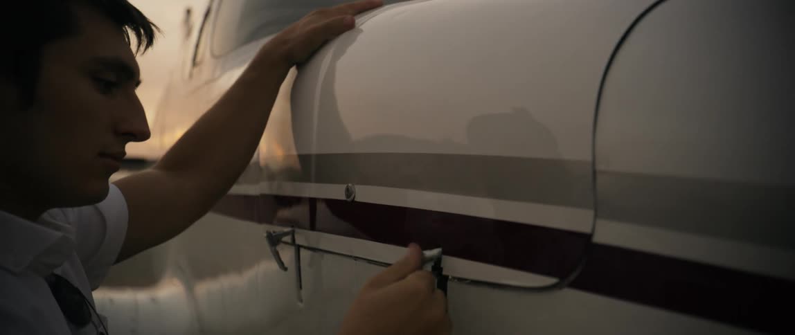 Male pilot checking the side of a plane with luggage