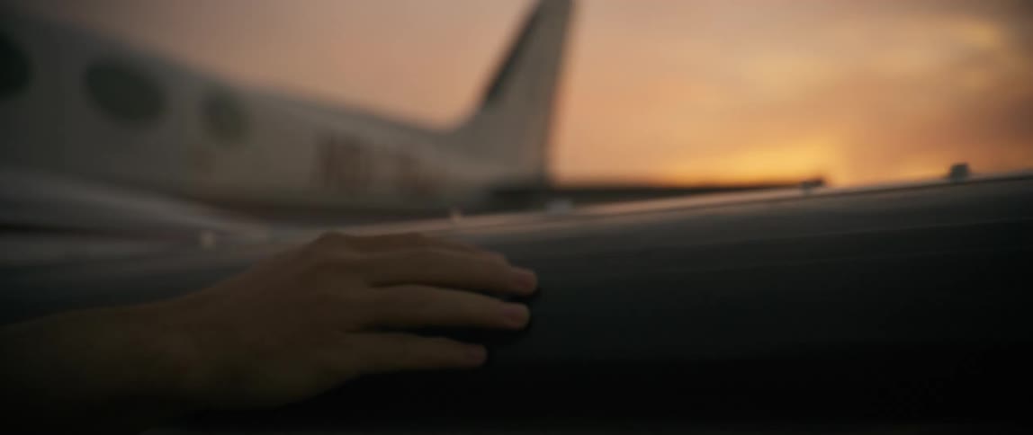 Hand being passed over the wing of an airplane