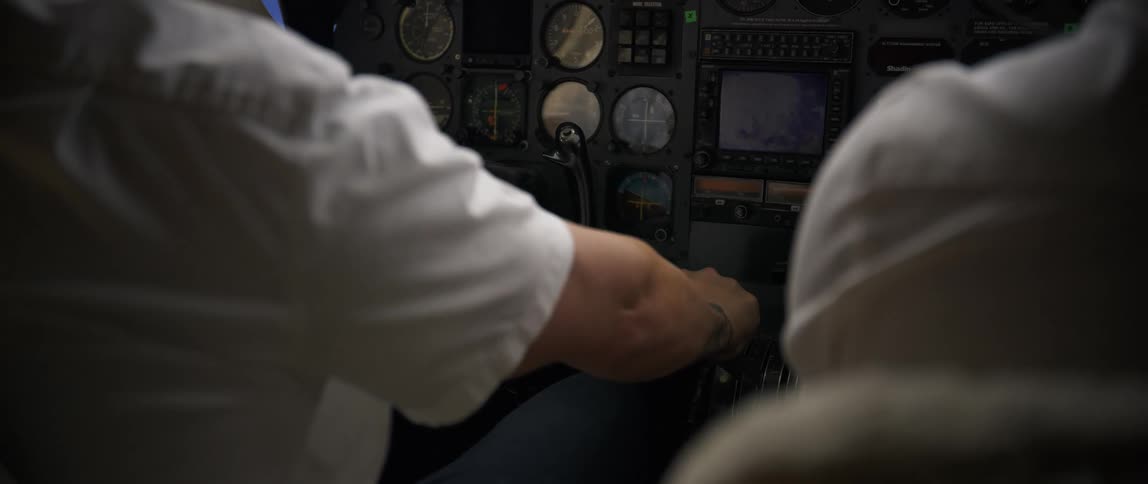 An airplane pilot preparing for takeoff moving the throttle with the copilot beside him