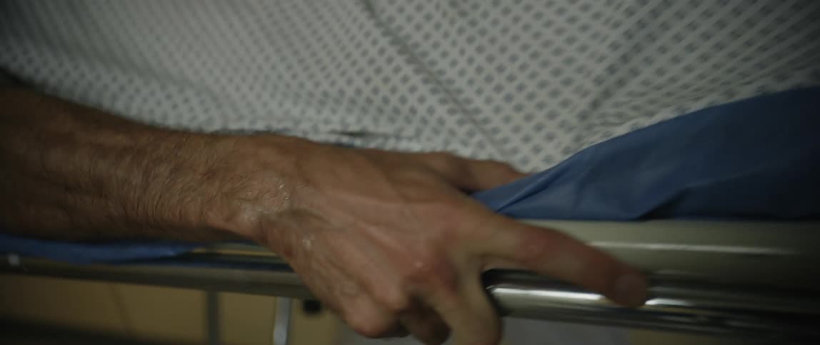 A medical worker rushes a patient on a gurney down the hallway of a hospital
