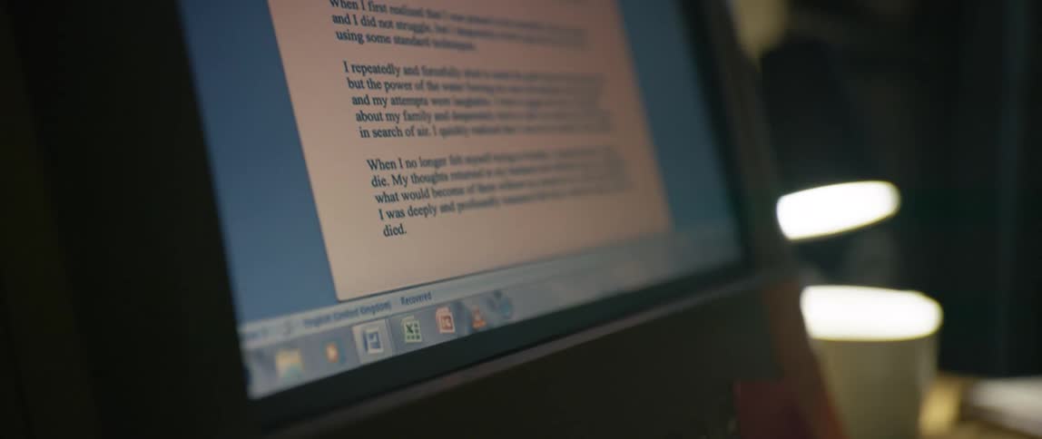 Closeup of a computer screen displaying a document and a mug next to it