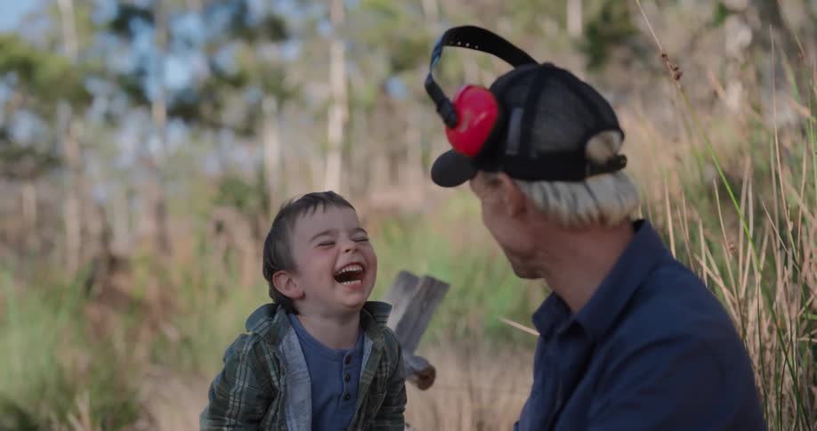 A boy takes off his headphones and puts it on his father