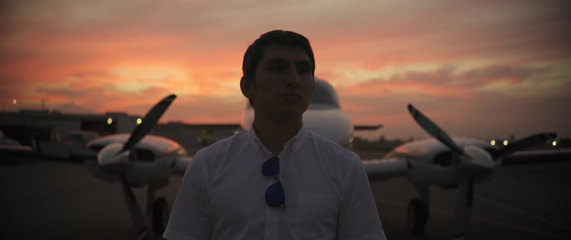 An airline pilot stands on the runway among airplanes and is deep in thought