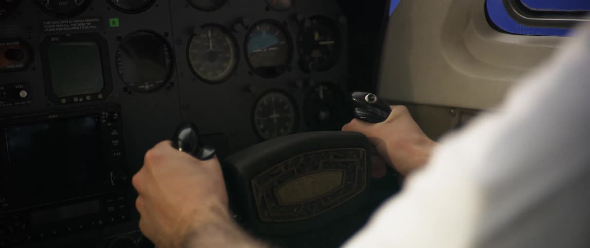 A pilot firmly holds the yoke at the cockpit in position with both hands