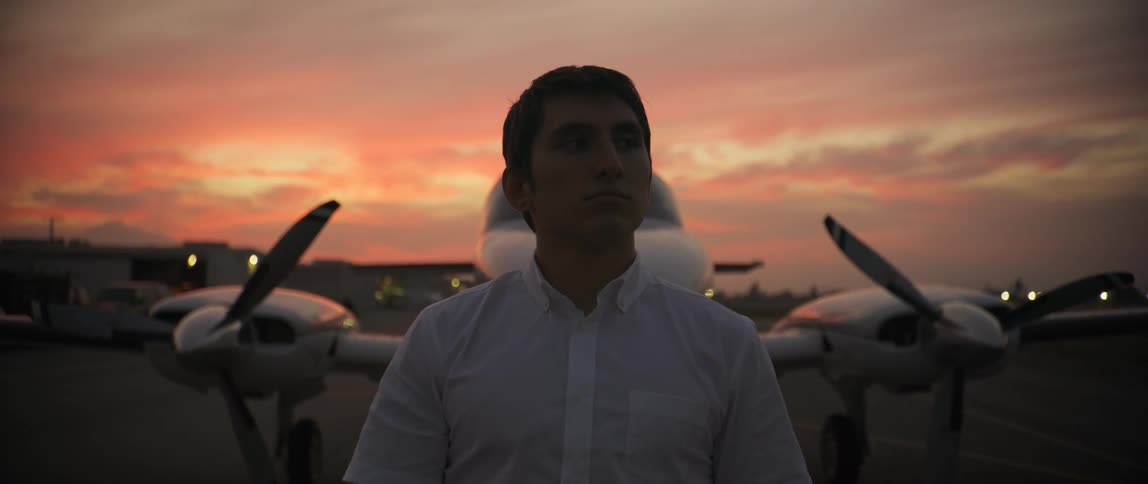 Man in front of an airplane taking off his sunglasses in the late afternoon