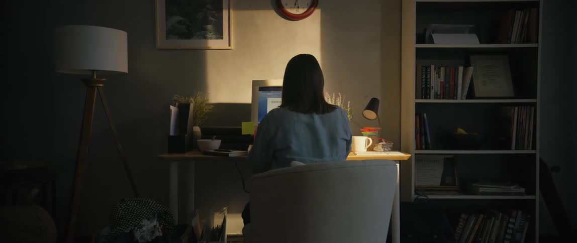 A woman is sitting at her desk using a computer