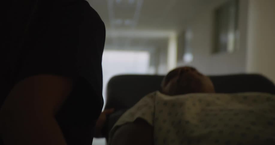 A patient is being pushed down the hallway on a gurney