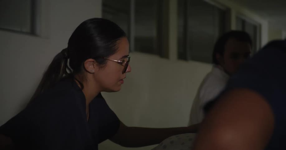 Two er nurses wheeling in a patient in a hospital