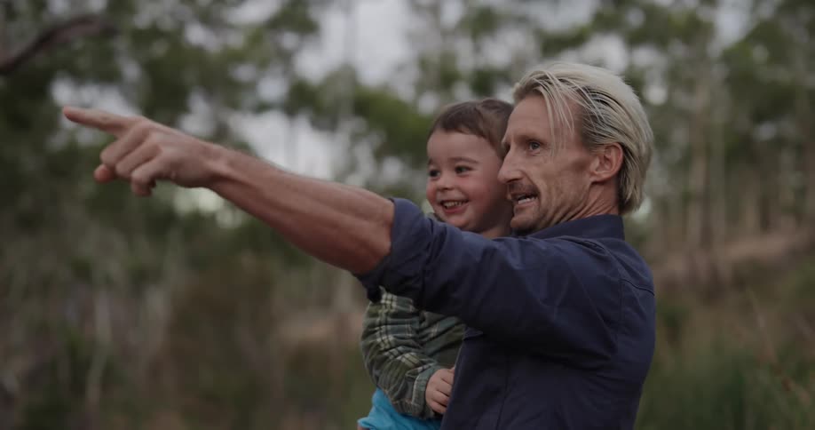 Father with his little son on his lap in a place surrounded by trees