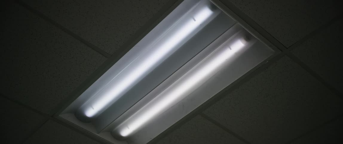 A double light bulb on the white ceiling that is turning on and off