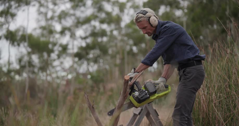 The man cuts a small log with his chainsaw