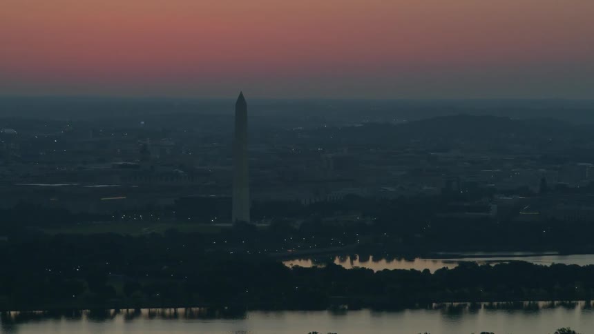 The washington monument stands against the dusk sky
