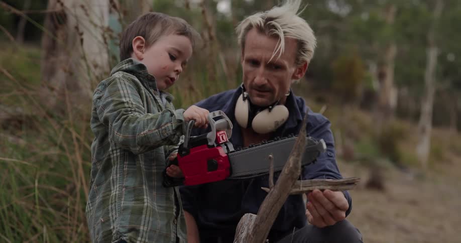 A boy plays with a toy chainsaw pretending to cut branches