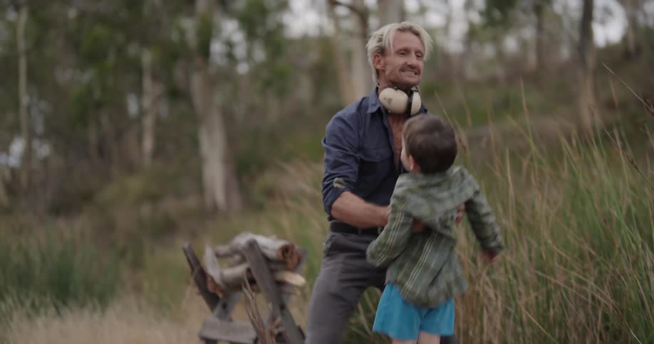 Father in a natural environment with trees holding his son in his arms