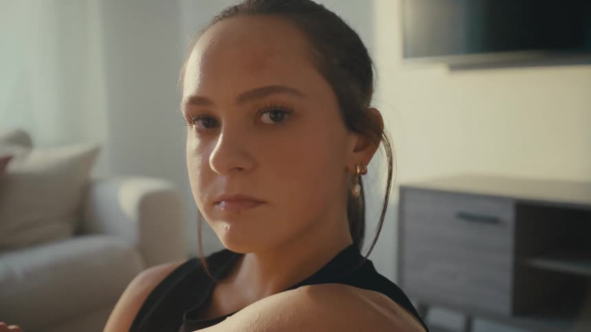 A woman stares into the camera in her living room