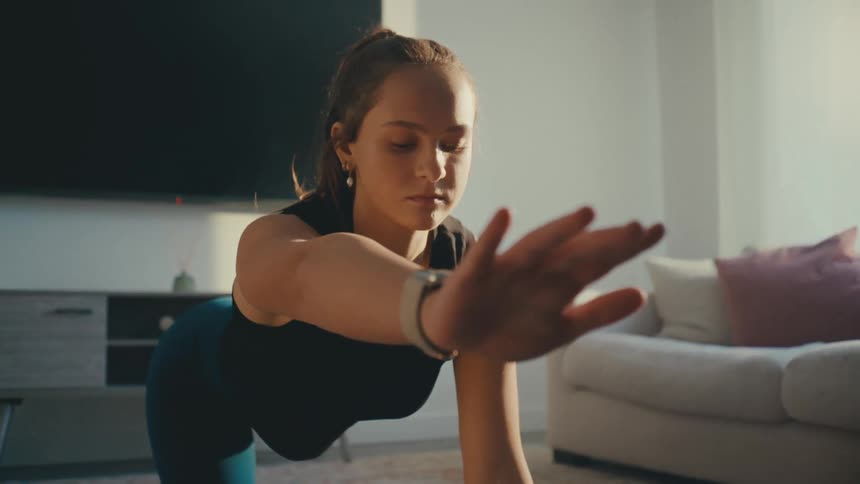 A young woman does yoga in a living room on the floor