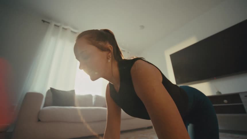 A woman stretches and exercises on the floor in a living room