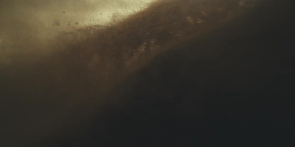 Flying through swirling sand as it is thrown into the air resembling a storm or earthquake with particles surrounding us and partially obscuring the bright sun
